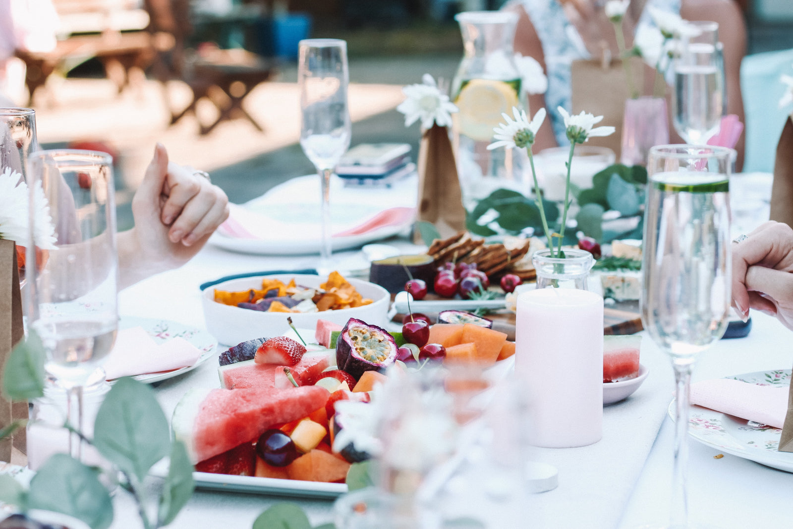 An outside dining setting with a Spring/Summer food spread. A bright and airy party or BBQ. 